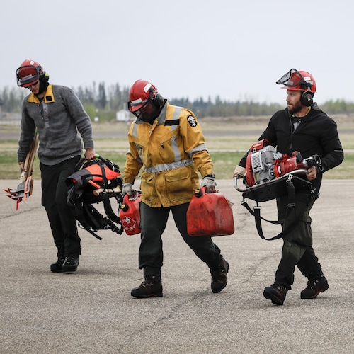Une équipe d'Alberta Wildfire marche sur le tarmac. 