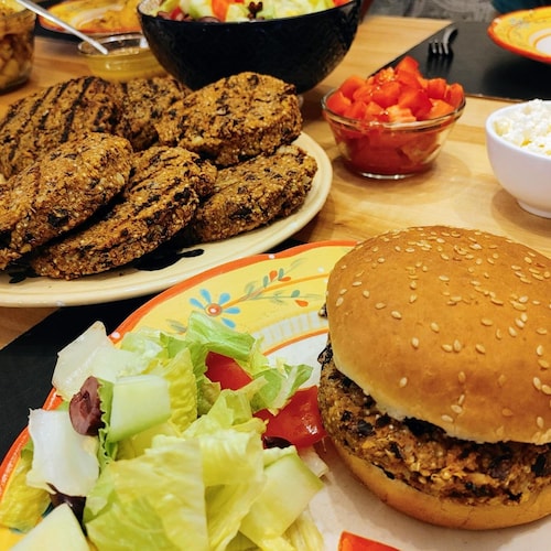 Des boulettes sont posées sur une table et un burger est placé dans une assiette.