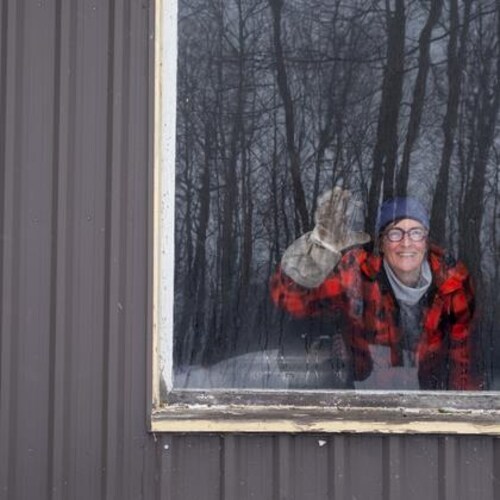 Izabel Zimmer salue la photographe à travers la fenêtre de son érablière.