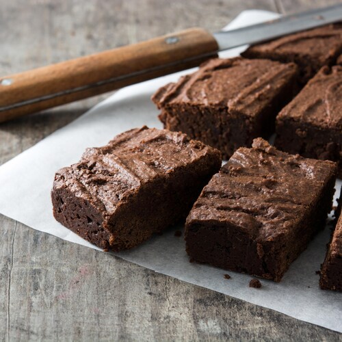 Un brownie coupé en morceau sur un papier ciré.