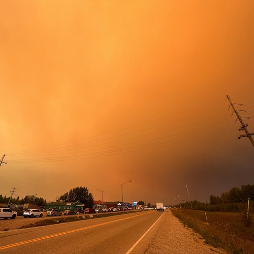 Des voitures alignées sur la route, sous un ciel orange, dimanche après-midi le 13 août 2023.