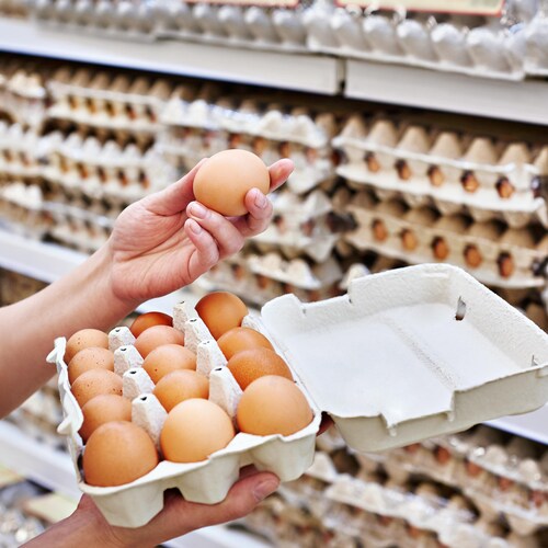 Une femme tient un carton d'oeufs dans un supermarché.