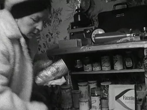 Femme chaudement habillée remplissant les tablettes de conserves de son abri antinucléaire