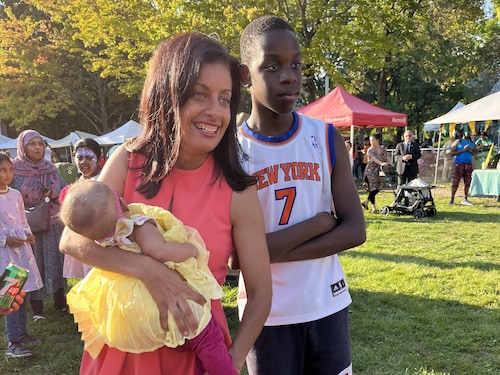 Dominique Anglade tient un bébé dans ses bras alors qu'un adolescent noir se trouve à ses côtés.