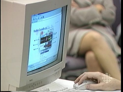Gros plan sur un écran qui montre le site web de Radio-Canada. Une main tient une souris d'ordinateur. 