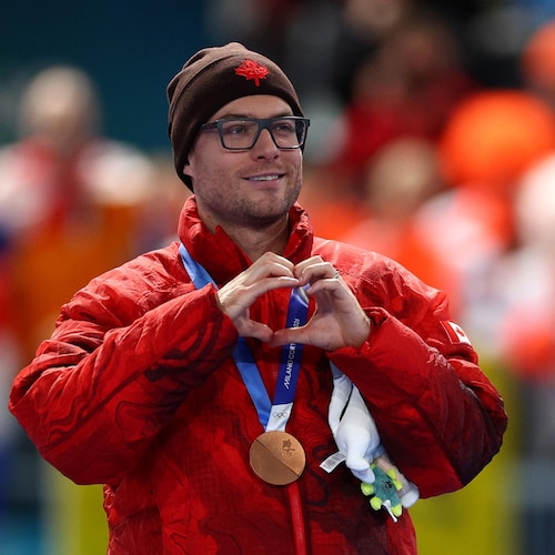 Il forme un cœur avec ses mains en regardant vers la foule.