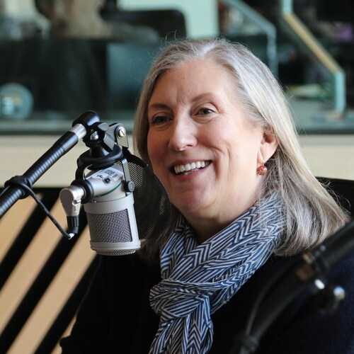 Une femme parle en souriant dans un micro, dans un studio de radio. 