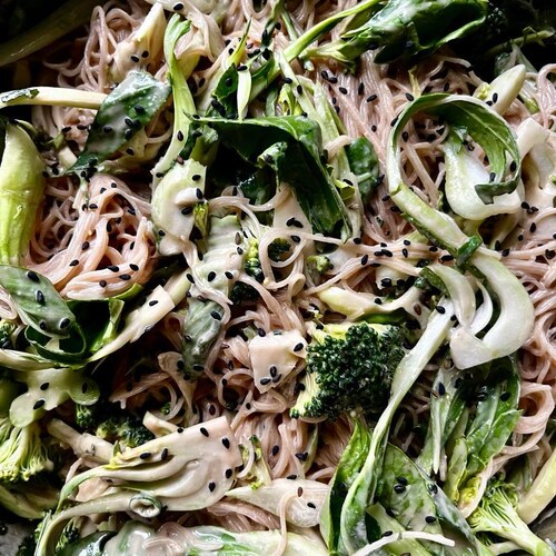 Une salade qui comprend des vermicelles, de la verdure et des graines. 