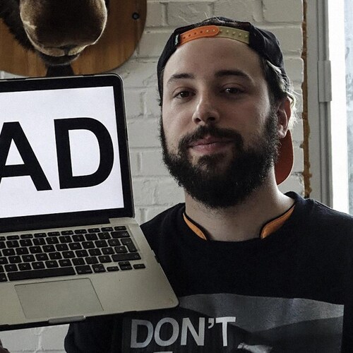 Une photo de Fred Bastien tenant un ordinateur avec la mention #AD.