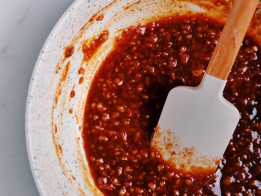 Une bol de sauce de sirop d'érable, sauce soya et noix hachées avec une spatule reposant dans le bol.