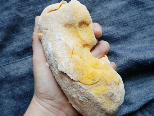 Une main tient une boule de pâte au-dessus d'une nappe en denim.