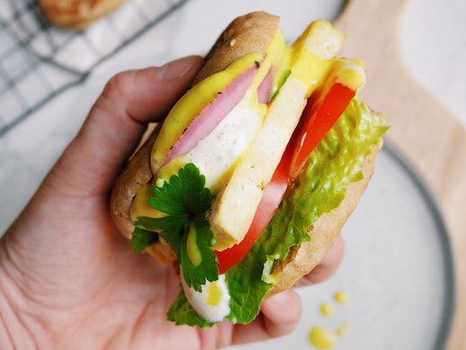 Une main tient un sandwich déjeuner végétalien de côté.