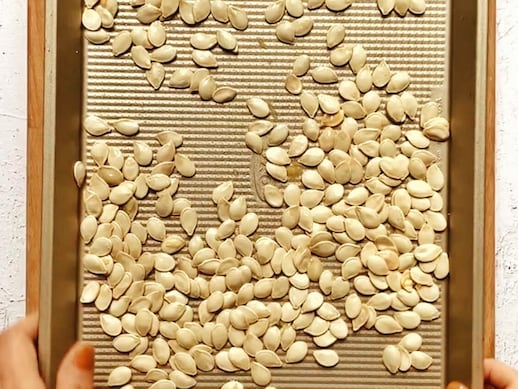 Des graines de citrouille crues sur une plaque à cuisson.