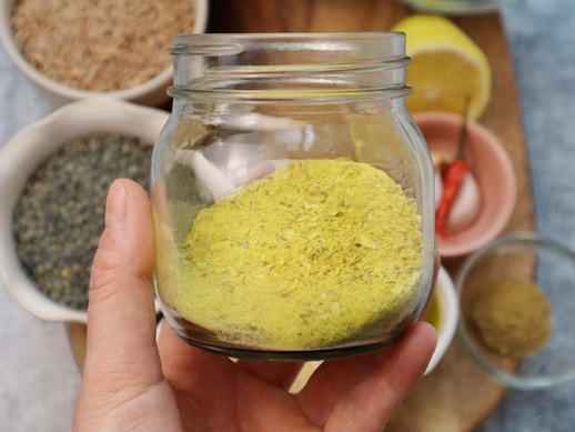 Une main tenant un pot en verre contenant de la poudre à bouillon instantané.