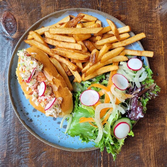 Une guédille de homard avec des frittes et une salade dans une assiette.