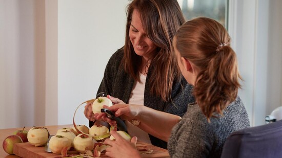 Geneviève et sa fille Maude, sont assise à la table de cuisine et elles enlèvent la pelure des pomes.