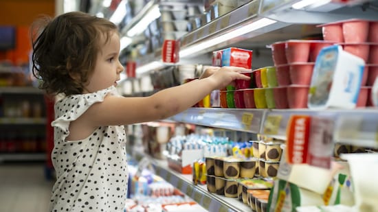 Une petite fille est attiré par l'emballage coloré d'un produit au supermarché.