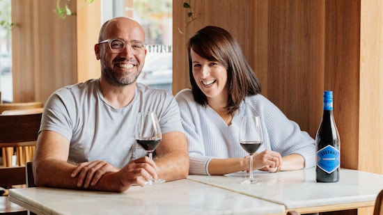 Geneviève O'Gleman et Stephano Faita attablés avec un verre de vin rouge.