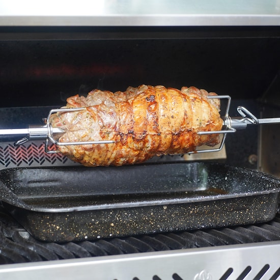Une pièce de viande sur une broche dans un barbecue.