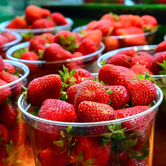 Des pots sont remplis de fraises. 