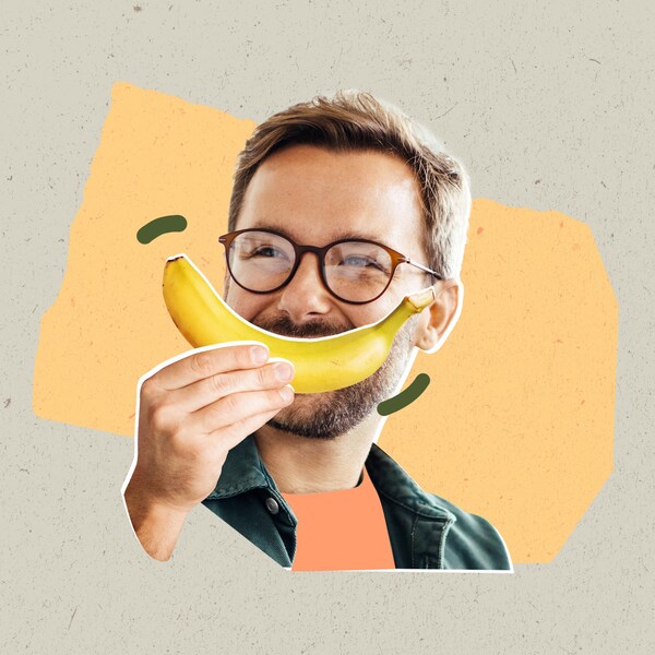 Un homme tient une banane devant son visage.