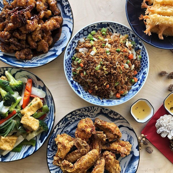 Des plats de mets asiatiques déposés sur une table à thématique Noël. 