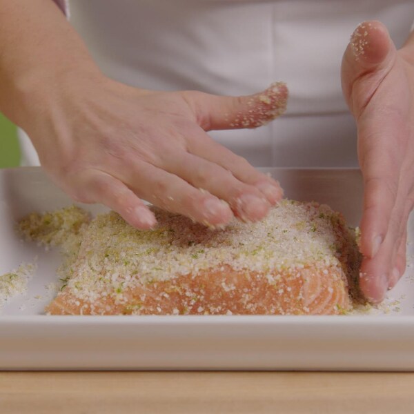 Une personne ajoute un mélange de saumure sur un filet de saumon.