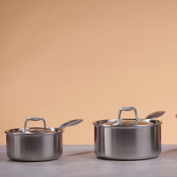 Une petite casserole, une grande casserole et un faitout sont posés sur une table de travail. 