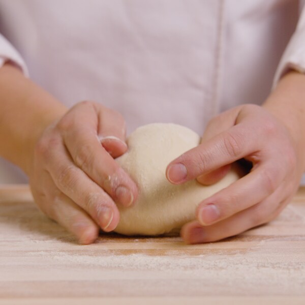 Une personne pétrit une boule de pâte à pain sur un ilot bien enfariné. 