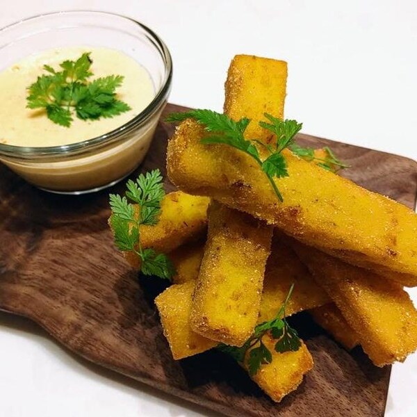Des bâtonnets de polenta grillés et un bol de sauce au maïs et fontina fumé.
