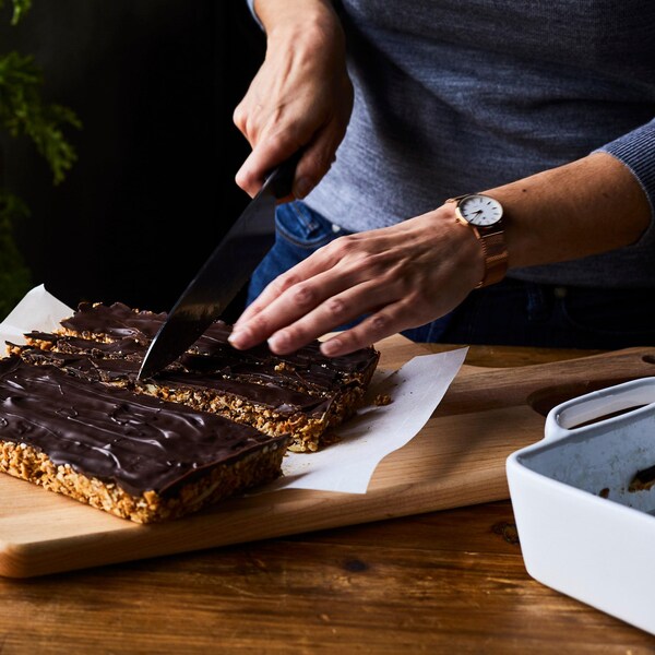 Femme qui tranche des barres tendres maison garnies de chocolat noir.