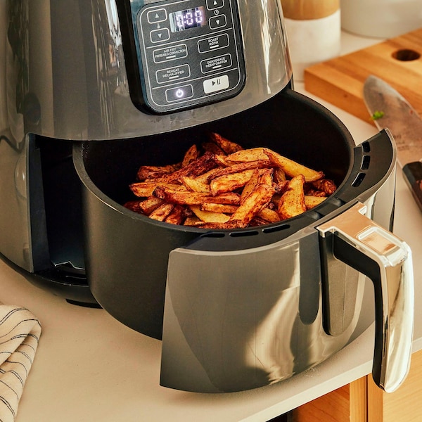 Des frites dans le tiroir ouvert d’une friteuse à air. 