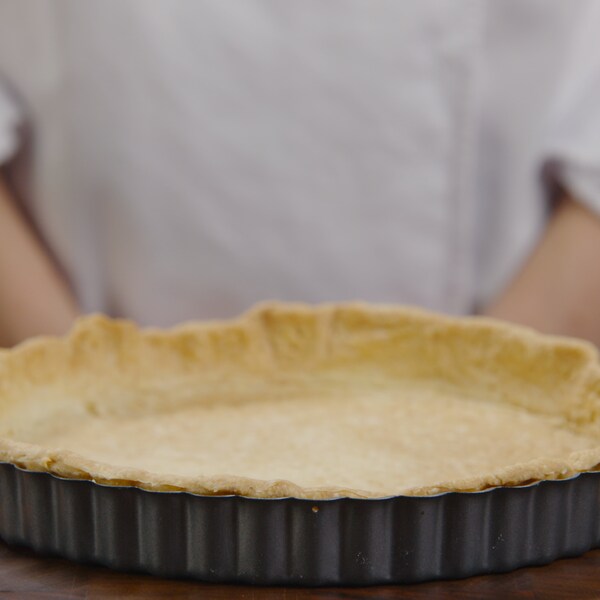 Un fond tarte fraîchement sorti du four repose sur un ilot de cuisine. 