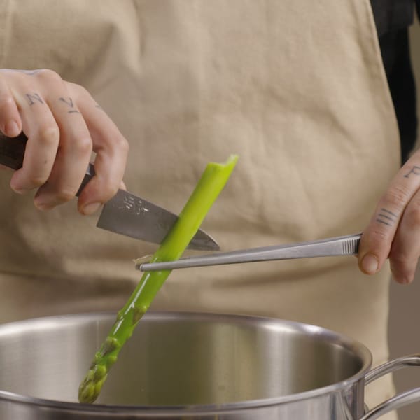 Une personne retire d'un chaudron une asperge pour savoir si elle est cuite. 