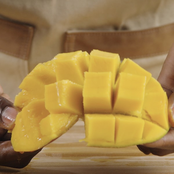 Une personne tient un morceau de mangue dans ses mains. 