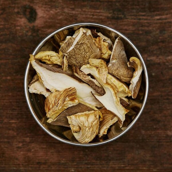 Un bol de champignons séchés est déposés sur un comptoir de bois. 