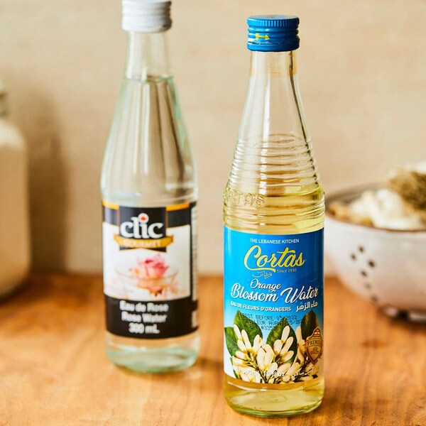 Deux bouteilles, une d'eau de rose et une d'eau de fleur d'oranger, sont déposées sur un comptoir de cuisine en bois.