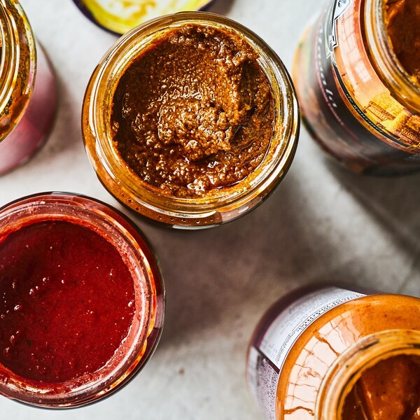 Cinq pots de pâtes de cari indiennes sur un comptoir.