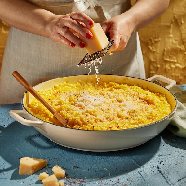 Un plat de risotto sur lequel on ajoute du fromage râpé.