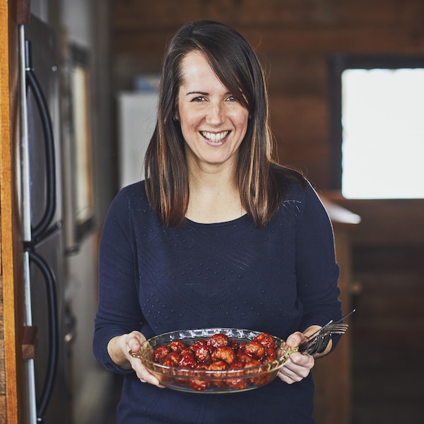 La nutritionniste Geneviève O'Gleman est debout dans la cuisine et tient un bol de nourriture et des ustensiles dans ses mains.