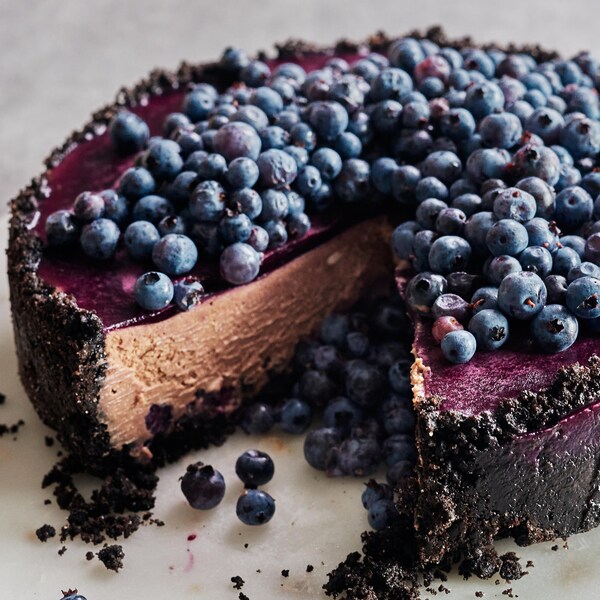 Un gâteau au fromage aux bleuets et au chocolat dans une assiette avec une part manquante.