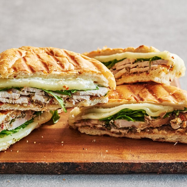 Des paninis au rôti de porc sur une planche de service.