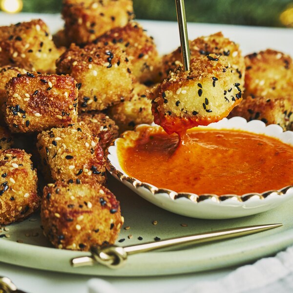 Des bouchées de halloumi frit dans une assiette avec un bol de sauce.