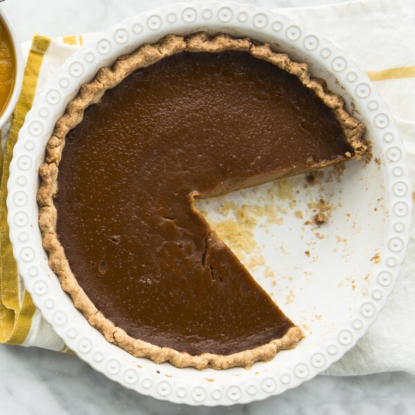 Une tarte à la citrouille et au caramel et quelques pointes dans des assiettes avec de la crème fouettée. 