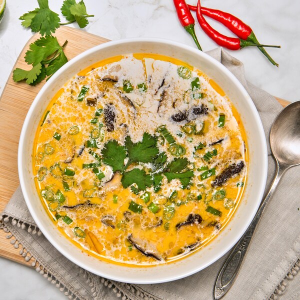 Un bol de soupe garni, un bol de nouille de riz, des quartiers de lime, de la coriandre.