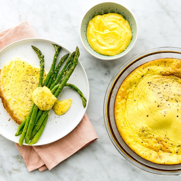 Une omelette dans une assiette avec des asperges recouvertes de sauce maltaise.
