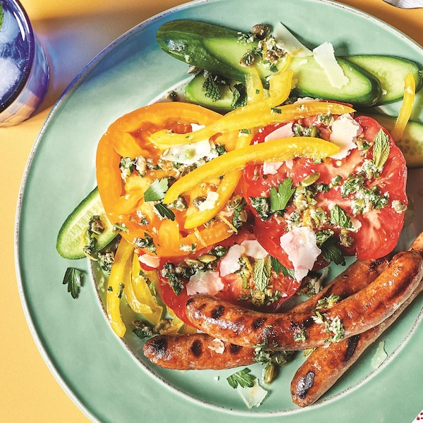 Des merguez accompagnées de légumes dans une assiette.