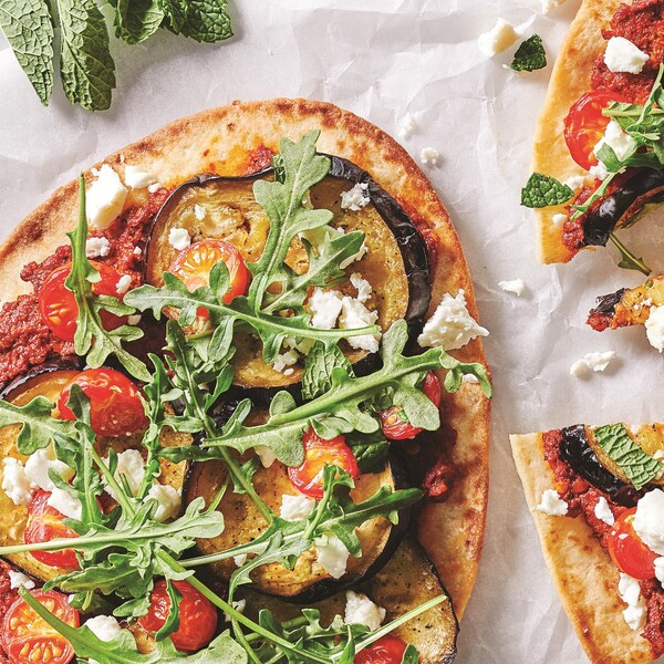 Une pizza aux aubergines complète et une coupée en morceaux.