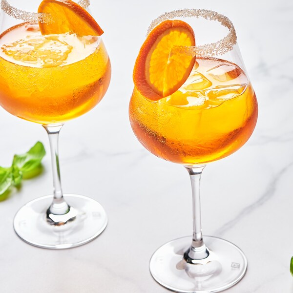 Des coupes à vin contenant du spritz pomme-gingembre garnies de tranches de pomme.