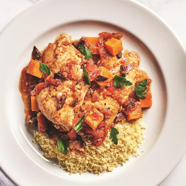 Une assiette rempli d'un one pot d'escalopes de poulet, de patate douche et d'olives.
